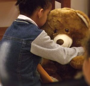 Criança abraçando um urso de pelúcia
