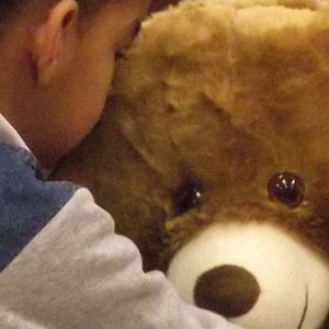 Criança abraçando o urso Teddy com tecnología embutida.