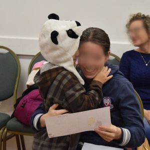 Un niño abraza y muestra su dibujo a su mamá.