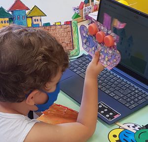 Criança mostrando para o computador um barco de artesanato com sucata