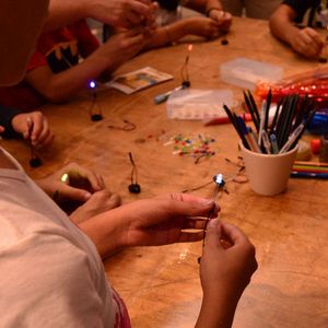 Los participantes están creando circuitos electrónicos con LEDs y pilas en forma cilíndrica. 