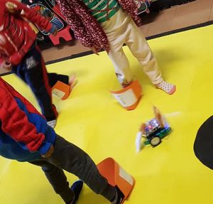 Niños con botas de EVA personalizadas, alrededor de un pequeño robot disfrazado de lobo.