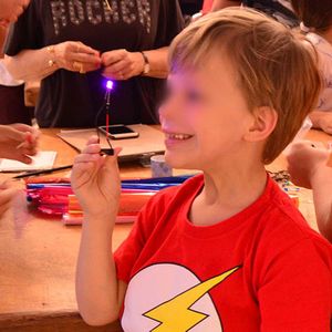 Un niño sonriente muestra su LED encendido.