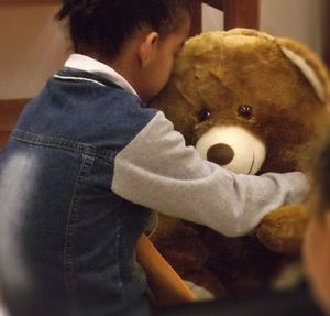 Niño abrazando a un gran oso de peluche.